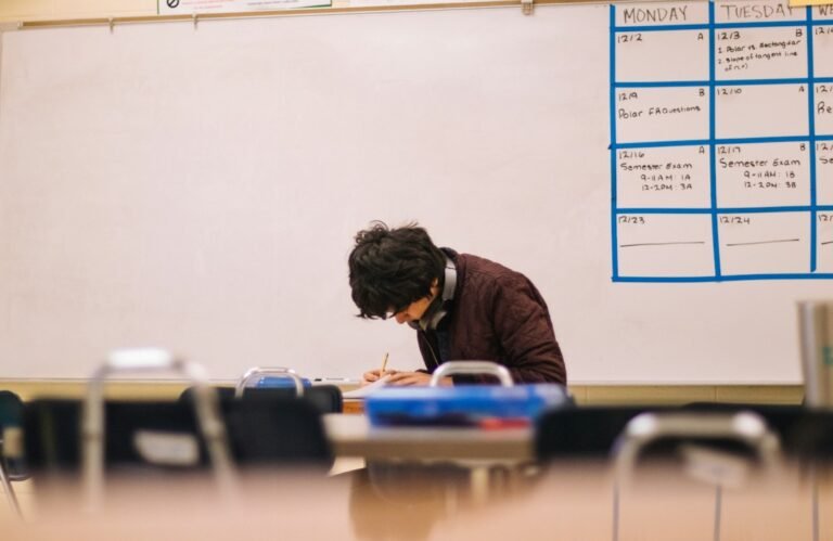 Student writing grammar practice answers in a classroom notebook