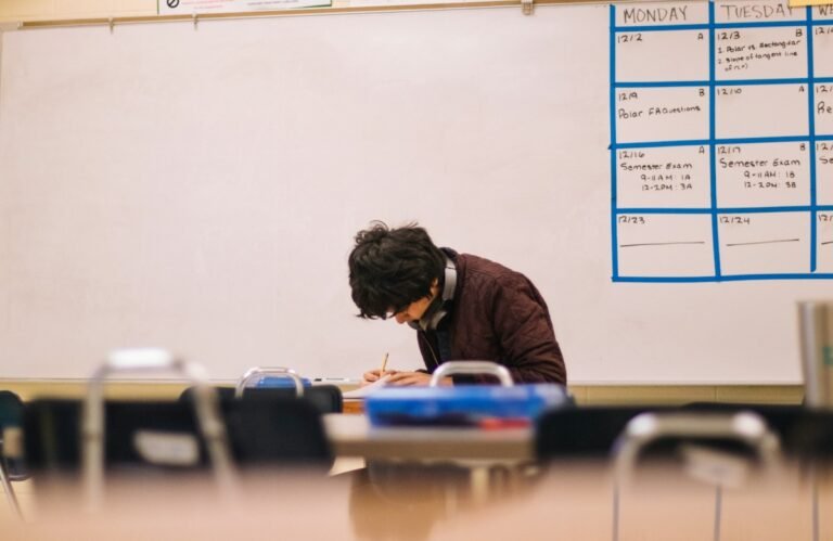 Student writing at a classroom desk illustrating observational data collection